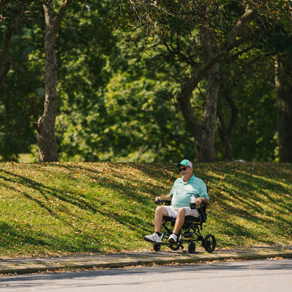 Man in a Jazzy carbon HD on a path in a park with trees in the background