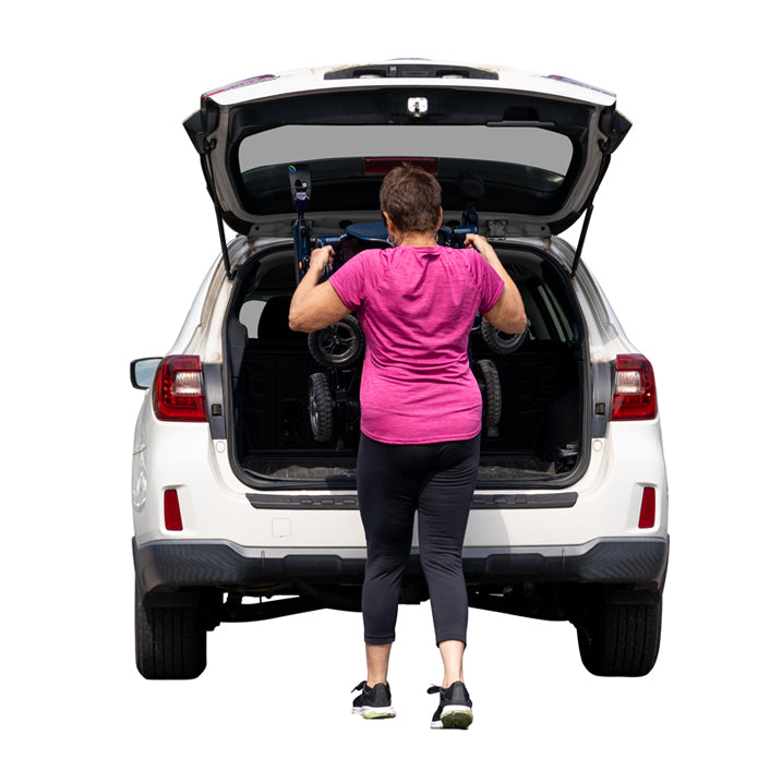 Person loading a Pride jazzy carbon 27 night sky into the trunk of a white SUV on a white background