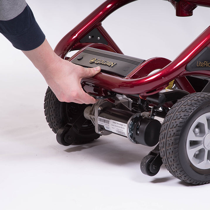 Hand holding a battery pack on a red go-kart with 'Goudi' branding.