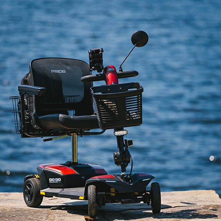 Pride Go-Go Endurance AL+ scooter  with a basket on a dock by water