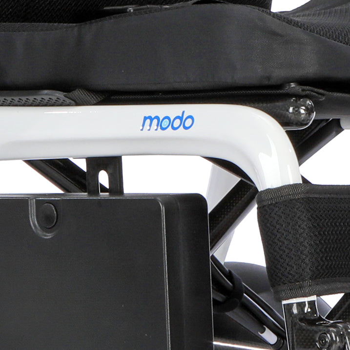 Close-up of a white Modo wheelchair frame with blue logo lettering, black seat cushion, and black harness straps against a white background.