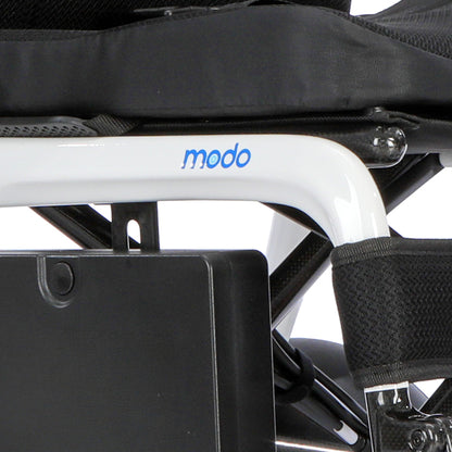 Close-up of a white Modo wheelchair frame with blue logo lettering, black seat cushion, and black harness straps against a white background.