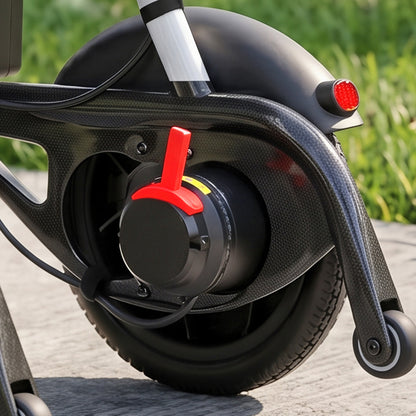 Close-up of the rear wheel and motor area Modo Breeze Ultralightweight Folding Electric Wheelchair showing a carbon-fiber textured frame, black tire, red handle-like accent on the motor, and a blurred outdoor background with grass and pavement.