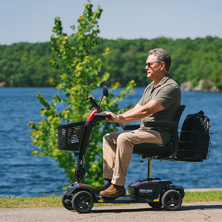 Man using a mobility scooter by a body of water with trees in the background