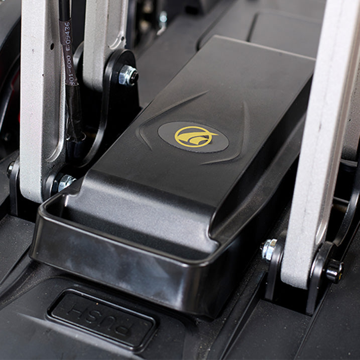 Close-up of a black foot pedal with a logo on a piece of exercise equipment.