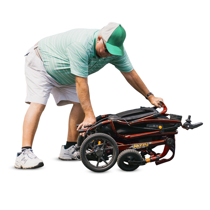 Man pushing a black and orange Jazzy scooter on a white background