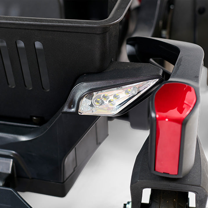 Close-up of a wheelchair headlight and turn signal with a black and red design.