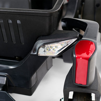 Close-up of a wheelchair headlight and turn signal with a black and red design.