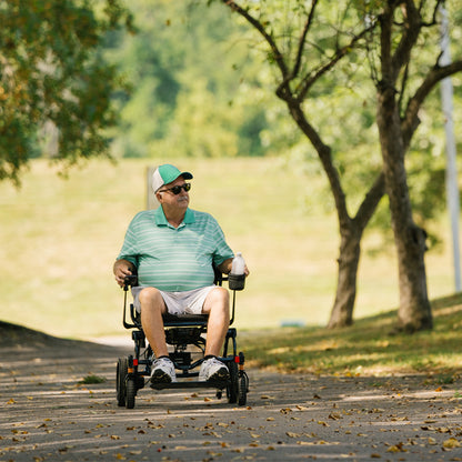 Man using a Jazzy carbon HD  in a park with trees and grass.